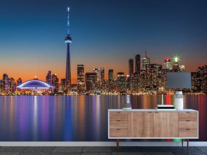 Toronto Skyline Wallpaper, as seen on the wall of this living room, is a photo mural of the CN Tower, Rogers Centre and twinkling skyscrapers reflected in Lake Ontario at night from About Murals.