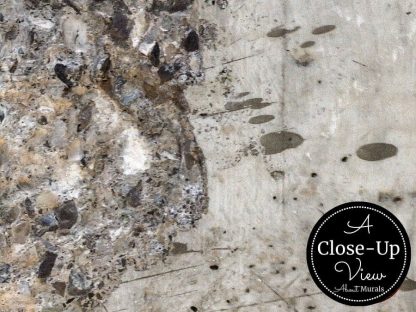A close-up view of the textured pebbles in an aged concrete wallpaper from About Murals.
