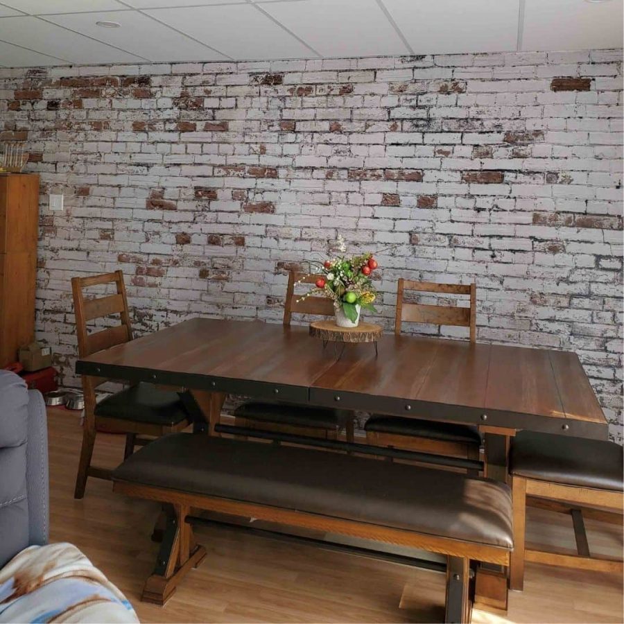 Distressed Brick Wallpaper, as seen on the wall of this dining room, features decaying white paint over red brick from About Murals.