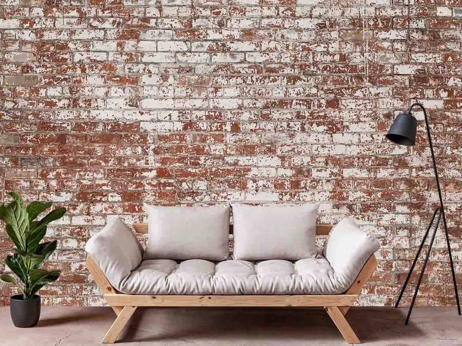 Grunge Brick Wallpaper, as seen on the wall of this living room, is a realistic photo mural with white paint peeling off red brick from About Murals.