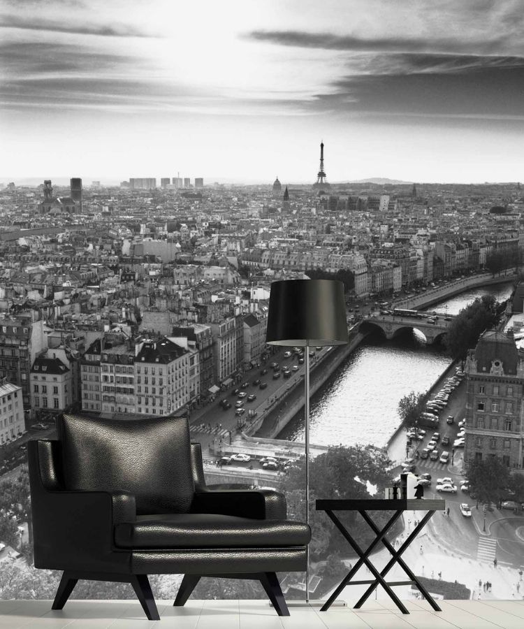 Paris Wallpaper, as seen on the wall of this living room, is a black and white photo mural of a Paris skyline featuring the Eiffel Tower, bridges over La Seine river, shops, restaurants and historical architecture from About Murals.