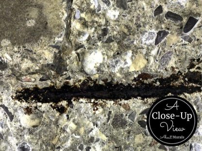A close-up of black, rusted rebar in a dark concrete wallpaper from About Murals