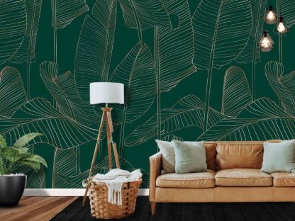 Banana Leaf Wallpaper, as seen on the wall of this dark green living room, is a tropical mural with gold banana leaves on a hunter green background from About Murals.