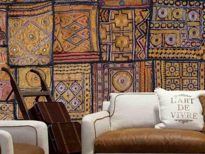 Carpet Wallpaper, as seen on the wall of this living room, features a patchwork rug full of gold, red, orange and purple circle, square, diamond and stripe patterns from About Murals.