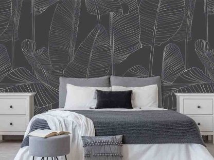 Grey Banana Leaf Wallpaper, as seen on the wall of this bedroom, is a tropical mural with the silhouette of big leaves on a dark gray background from About Murals.