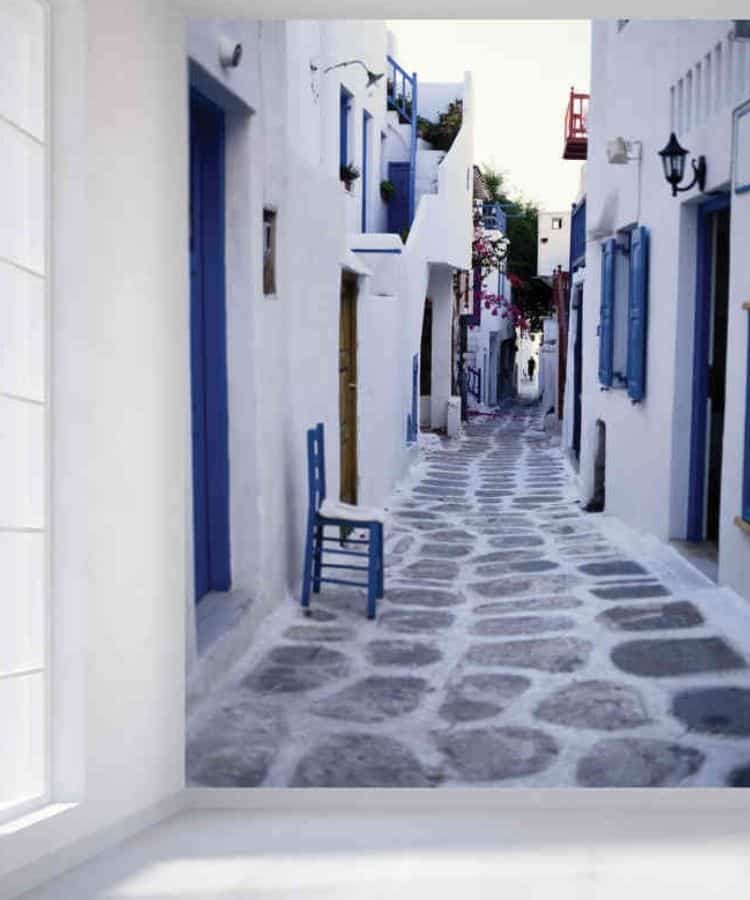 Mykonos Wallpaper, as seen on the wall of this room, features a cobblestone alley lined with whitewashed architecture on Matoyianni Street in Greece from About Murals.