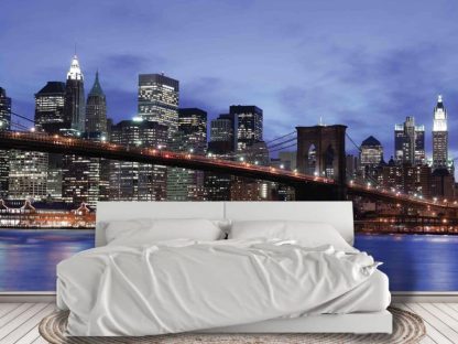 NYC Skyline Wallpaper, as seen on the wall of this bedroom, is a photo mural of buildings, skyscrapers and the Brooklyn Bridge under a blue night sky in New York from About Murals.