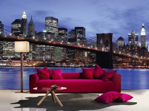 NYC Skyline Wallpaper, as seen on the wall of this living room, is a photo mural of the New York suspension bridge at night, against skyscrapers and the blue East River from About Murals.