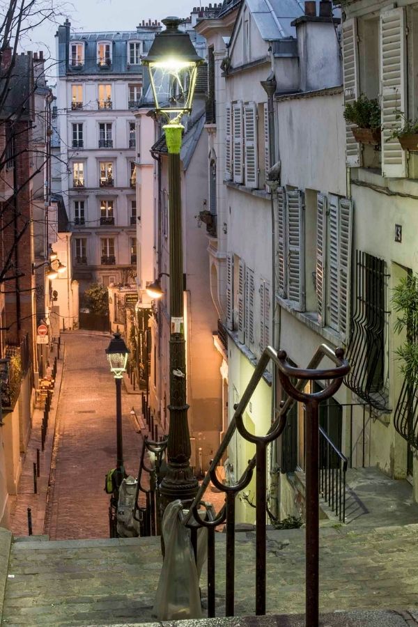 Paris Montmartre Wallpaper is a photo mural of the Butte de Montmartre and it's stairs leading past shops under street lights from About Murals.