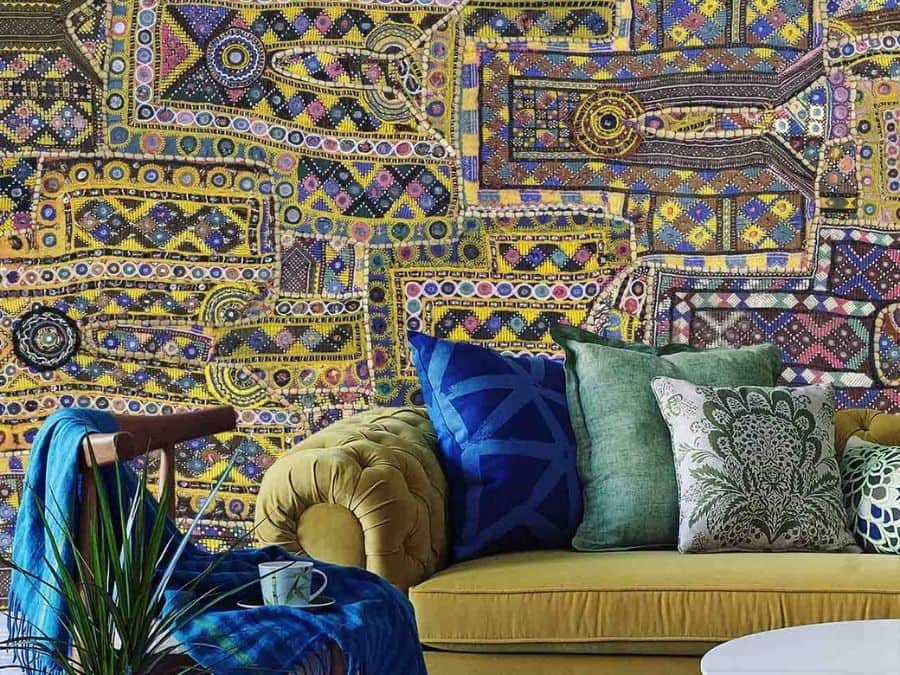 Patchwork Wallpaper, as seen on the wall of this living room, is a yellow and purple tapestry with tiny circle and square tiles from About Murals.