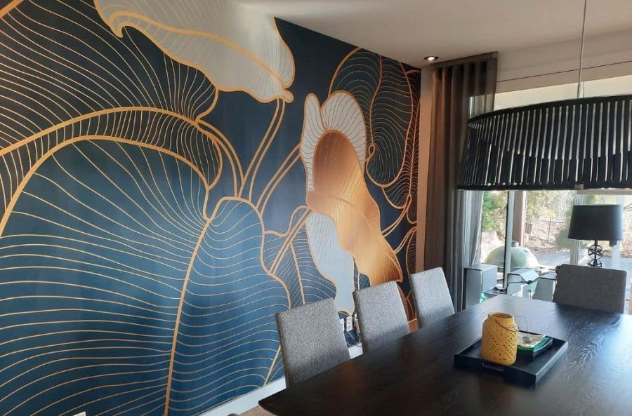 Philodendron Wallpaper, as seen on the wall of this dining room, is a big leaf mural with a tropical aesthetic from About Murals.