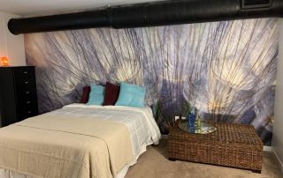 Purple Blue Dandelion Wallpaper, as seen on the wall of this loft bedroom, is a photo mural of a large flower up close from About Murals.