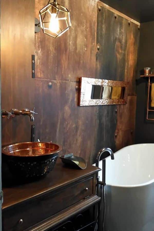 Rusted Metal Wallpaper, as seen on the wall of this master bathroom, features oxidized riveted metal panels from About Murals.