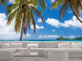 Beautiful Beach Wallpaper, as seen on the wall of this living room, is a photo mural of a panoramic beach with palm trees, blue ocean, white sand and tropical islands in the distance from About Murals.
