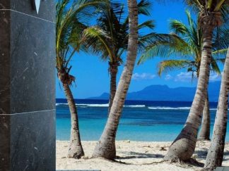 Blue Beach Wallpaper, as seen on the wall of this beach themed powder room, is a photo mural of a beach in Guadeloupe from About Murals.