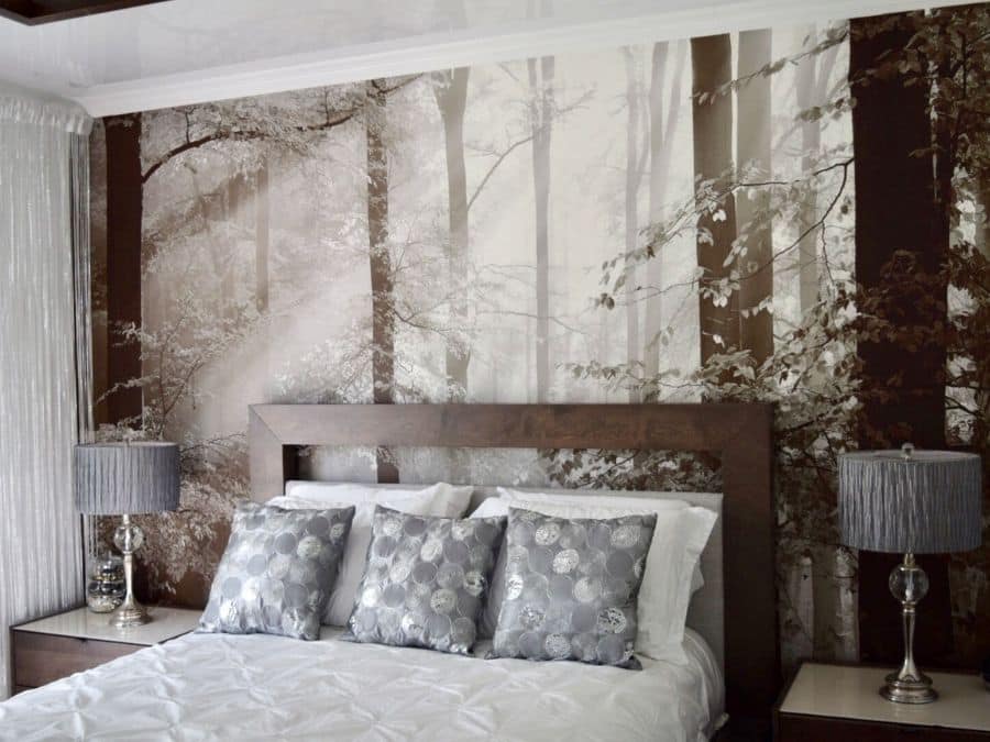 Brown Autumn Wallpaper, as seen on the wall of this bedroom, is a photo mural of sunbeams shining through trees in a forest from About Murals.