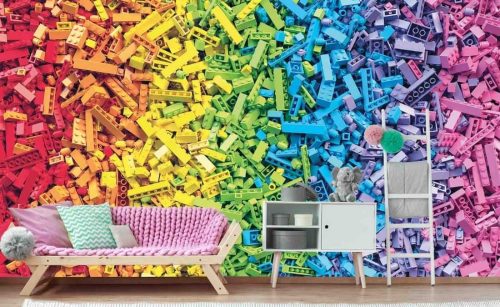Building Blocks Wallpaper, as seen on the wall of this Lego themed living room, is a mural with colorful plastic toy blocks piled in rainbow stripes from About Murals.
