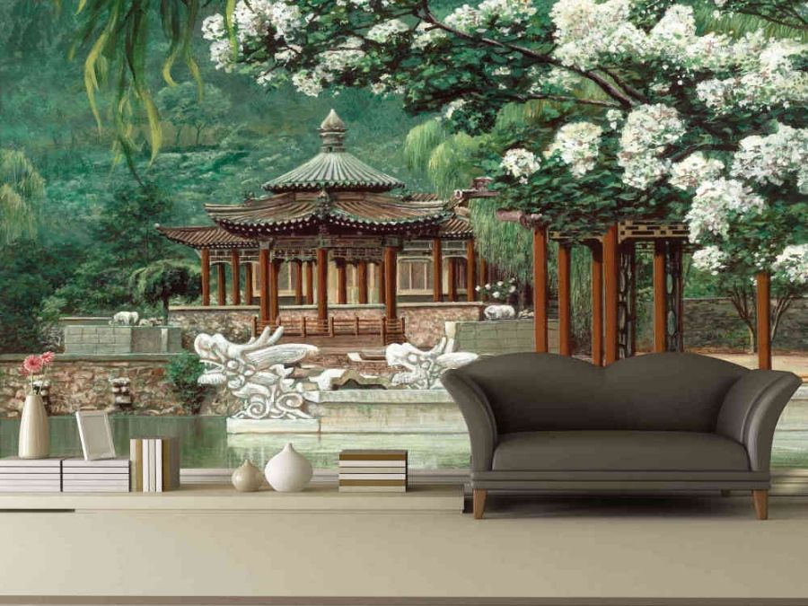 Chinese Temple Wallpaper, as seen on the wall of this living room, is a spiritual mural of an oriental structure surrounded by cherry blossom trees, green foliage and a zen pond from About Murals.
