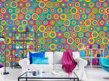 Colorful Circles Wallpaper, as seen on the wall of this living room, is a mural with concentric colored circles like pink, purple, orange, green, blue and yellow from About Murals.