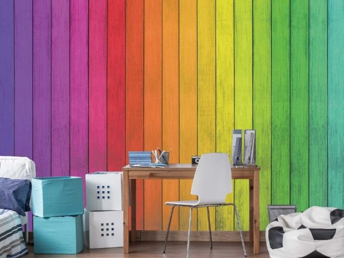 Colorful Wood Wallpaper, as seen on the wall of this rainbow colored room, is a kids mural with blue, purple, pink, red, orange, yellow, green and turquoise planks from About Murals.