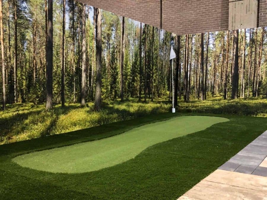 Fir Wallpaper, as seen on the wall of this indoor putting green, is a photo mural of pine trees and fir trees under a blue sky from About Murals.