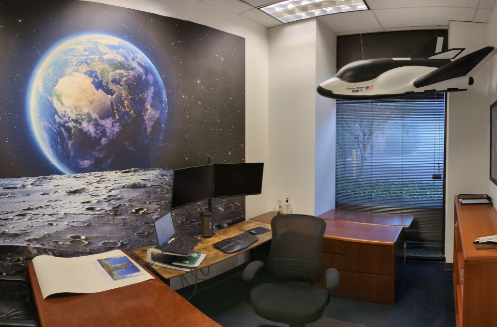 Space Earth Wallpaper, as seen on the wall of this space themed office with a flying dreamchaser hanging from the ceiling, is a space wall mural with a realistic view of the earth as seen from the moon by About Murals.