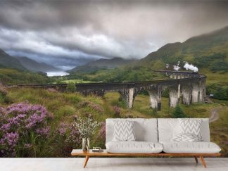 Steam Train Wallpaper, as seen on the wall of this living room, is a photo mural of a steam engine passing over Glenfinnan Viaduct in Scotland surrounded by a panoramic nature scene from About Murals.
