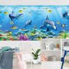 Under the Sea Wallpaper, as seen on the wall of this underwater bedroom, is a mural with dolphins and fish swimming around colorful coral from About Murals.