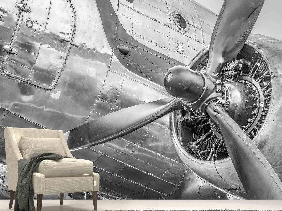 Vintage Airplane Wallpaper, as seen on the wall of this aviation themed living room, is a photo mural of a black and white plane propeller engine from About Murals.