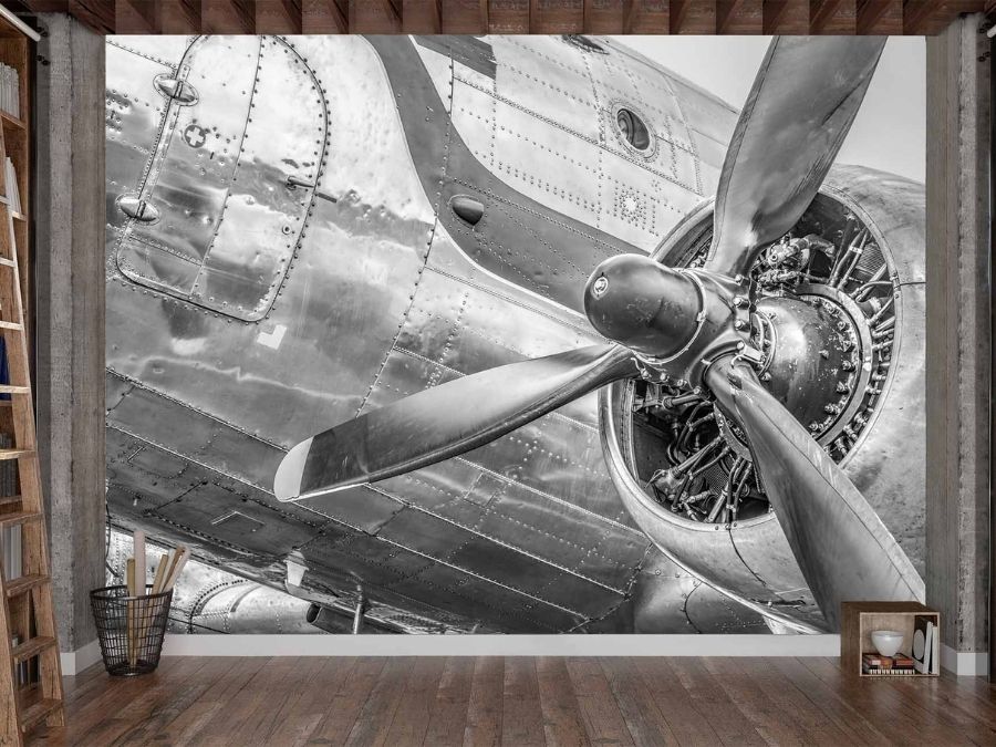 Vintage Airplane Wallpaper, as seen on the wall of this aviation themed room, is a photo mural of a black and white airplane propeller from About Murals.