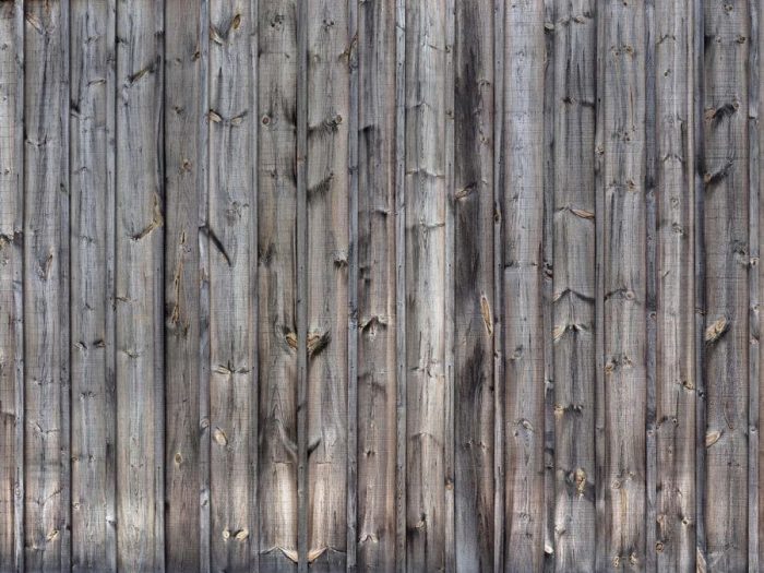 Wood Grain Wallpaper is a photo mural of gray old planks with knots and cracks from About Murals.