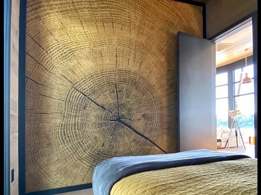 Wood Slice Wallpaper, as seen on the wall of this bedroom, is a photo mural of a chopped log with its annual rings and textured cracks from About Murals.
