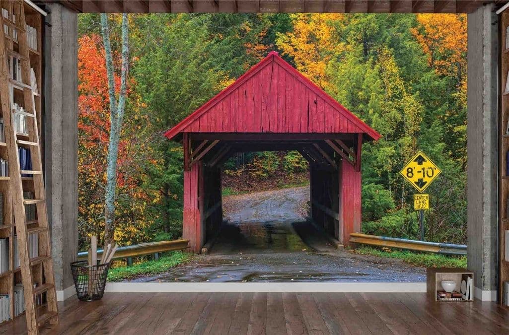 Covered Bridge Wallpaper, as seen on the wall of this room, is a photo mural of an old red wooden structure bordered by red and orange autumn trees in the country from About Murals.