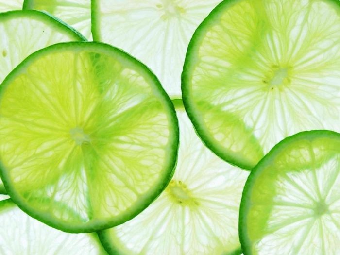 Green Lime Wallpaper is a photo mural of large green citrus slices on a white background from About Murals.