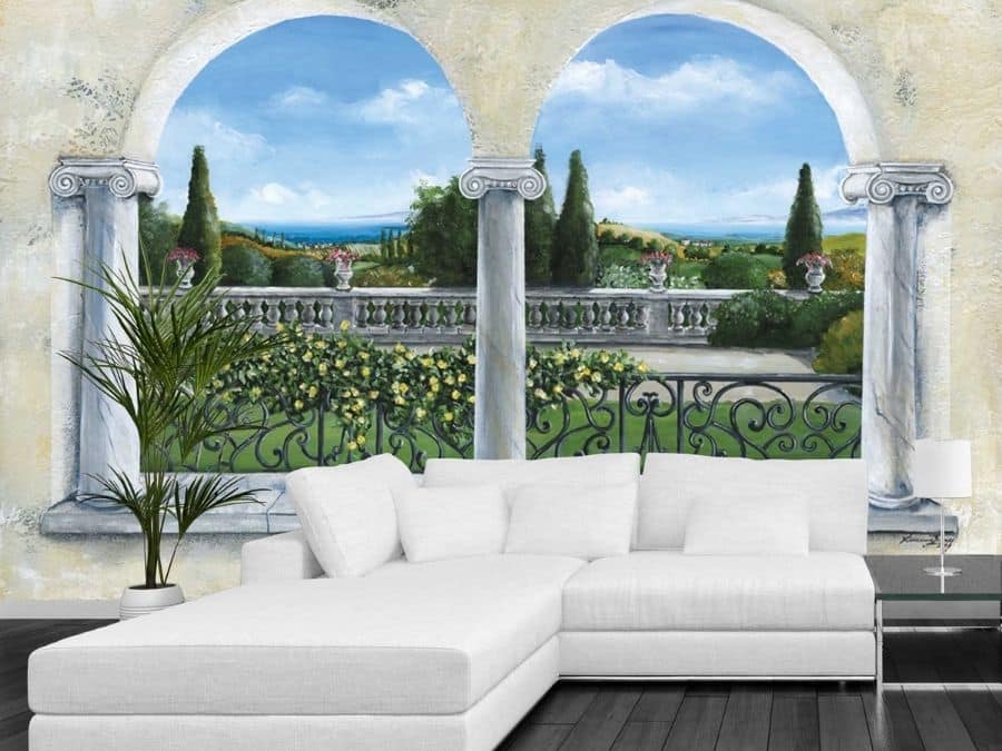 Italian Garden Wallpaper, as seen on the wall of this living room, is a mural of two arch windows in an Italian villa looking over a garden with plants, flowers and cypress tress from About Murals.
