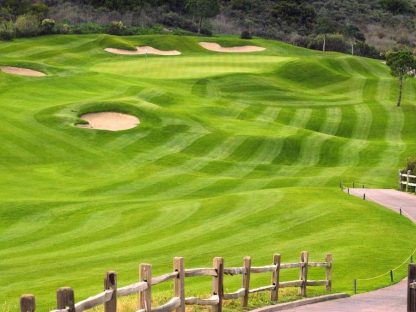 Golf Green Wallpaper is a photo mural of a signature hole surrounded by wavy grass, a bunker, cart path and wooden fence from About Murals.