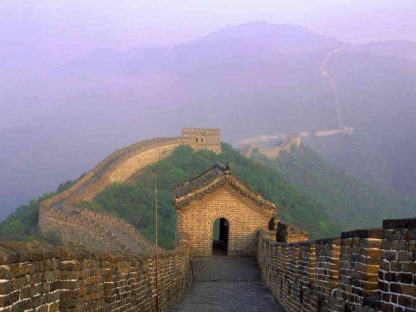 Great Wall of China Wallpaper is a photo wall mural of a walkway leading towards a guard tower and spanning across mountain ridges from About Murals.