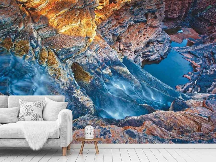 Blue Waterfall Wallpaper, as seen on the wall of this living room, is a photo mural of water gushing down layers of rock in a gorge from About Murals.