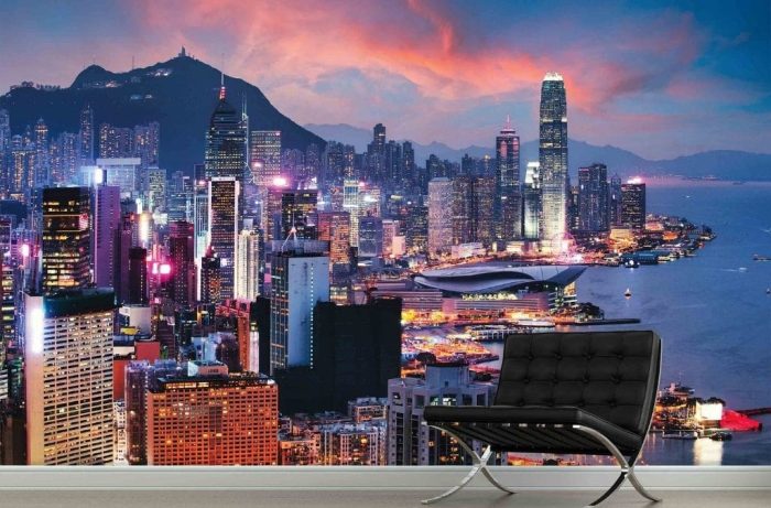 Hong Kong Wallpaper, as seen on the wall of this living room, is a photo mural of a sunset over China's Victoria Harbour and brightly lit skyscrapers from About Murals.