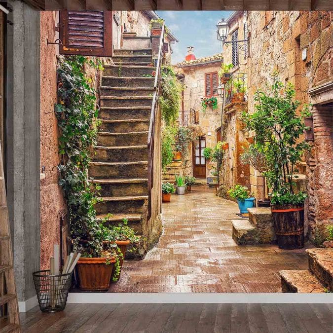 Italian Street Wallpaper, as seen on the wall of this room, is a photo mural of stairs leading to a cobblestone street near classic houses made of stone from About Murals.