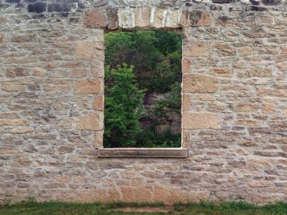 Forest Window View Wallpaper is a wall mural of a brown stone wall with an open window looking over green trees from About Murals.