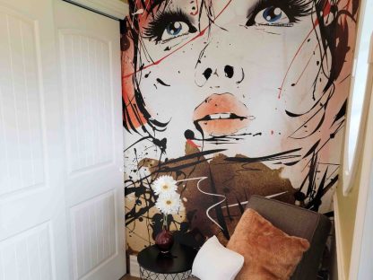 Pop Art Wallpaper, as seen on the wall of this bedroom, is a wall mural of a woman's face in a pop culture style from About Murals.