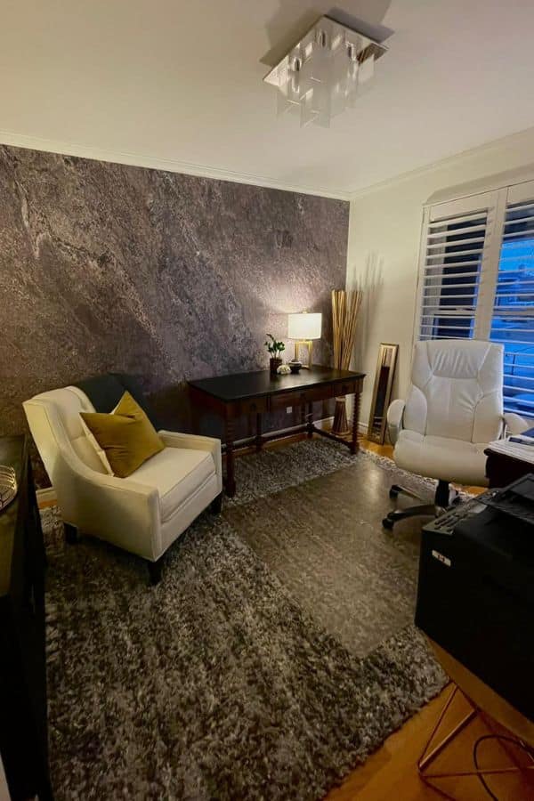 Stone Slab Wallpaper, as seen on the wall of this office, is a photo wallpaper of a modern grey textured stone wall from About Murals.