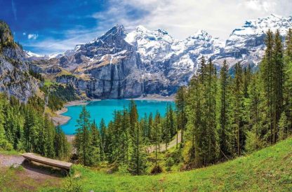 Swiss Mountain Wallpaper is a photo mural of snow capped mountains towering over a pristine turquoise lake surrounded by a pine tree forest from About Murals.
