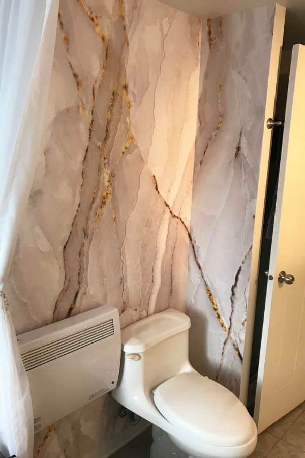 White and Gold Marble Wallpaper, as seen on the wall of this powder room, is a photo mural of white marble with golden veins from About Murals.