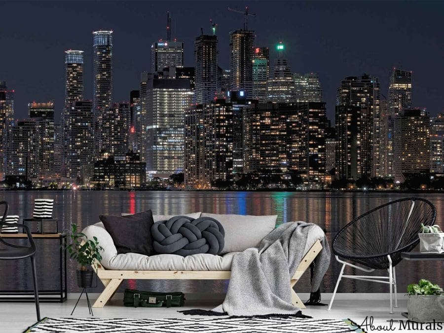 Downtown Toronto at Night Wallpaper, as seen on the wall of this living room, is a photo wall mural of buildings lit up against a dark sky that are reflected in Lake Ontario from About Murals.