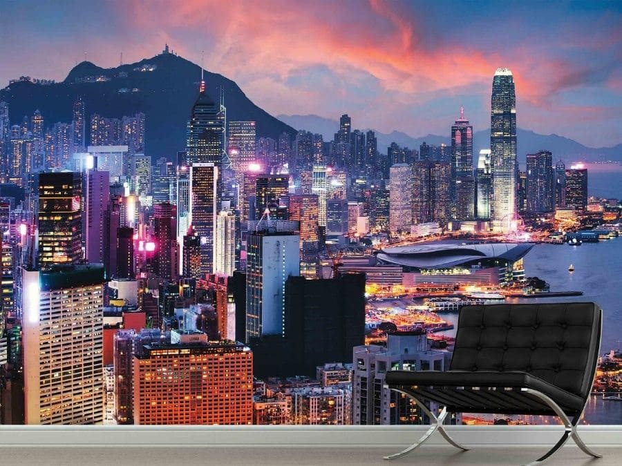 Hong Kong Wallpaper, as seen on the wall of this blue living room, is a photo mural of skyscrapers in Hong Kong under a pink and blue night sky from About Murals.