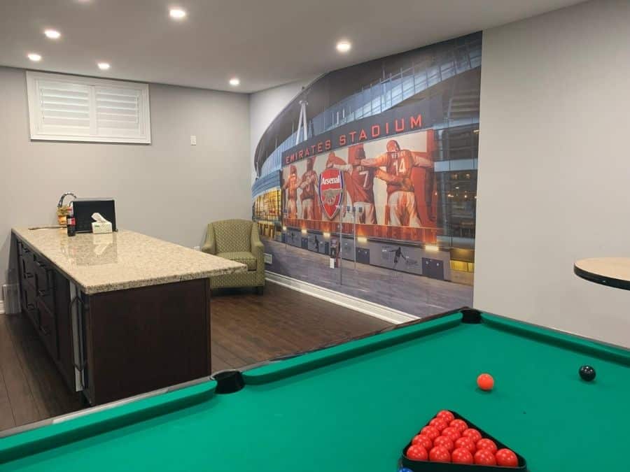 Custom photo wallpaper murals, like this stadium themed design in a Hamilton, Ontario home bar, are printed by About Murals.