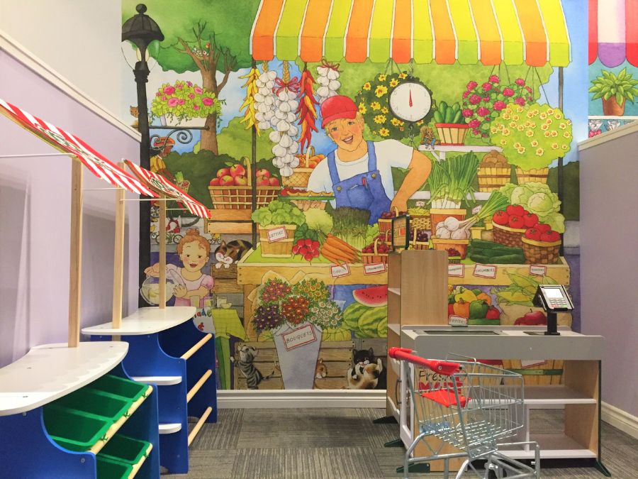 Grocery store mural, featuring a farmer selling fruit and vegetables, in a children's grocery store from About Murals.