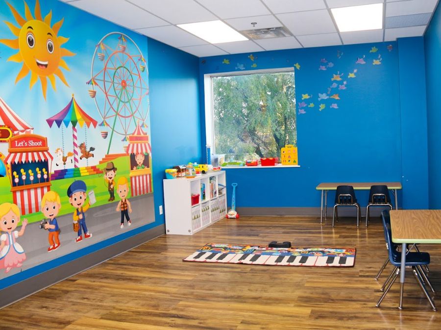 Indoor play area design ideas include a circus mural from About Murals, soft play toys, washable toys and desks.